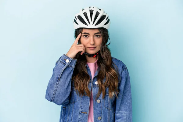 Young caucasian woman rinding a bike isolated on blue background pointing temple with finger, thinking, focused on a task.