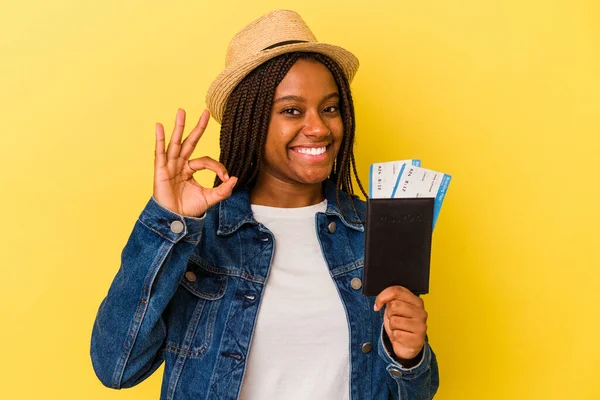 Pasaportu olan Afrikalı genç bir Amerikalı kadın sarı arka planda izole edilmiş neşeli ve kendinden emin..