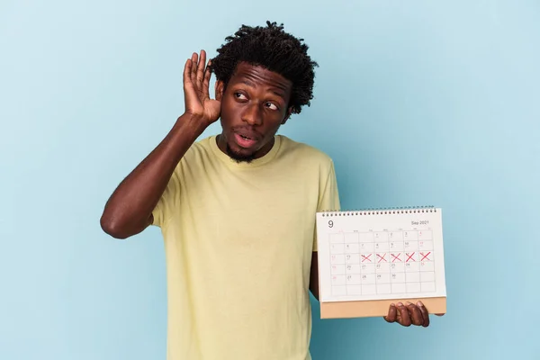 Jonge Afro Amerikaanse Man Houdt Kalender Geïsoleerd Blauwe Achtergrond Proberen — Stockfoto