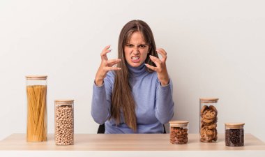 Beyaz arka planda izole edilmiş yemek tenceresi olan beyaz bir kadın gergin elleriyle çığlık atıyor..