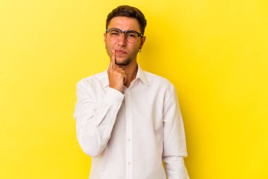 Sarı arka planda izole edilmiş dövmeleri olan genç, beyaz bir adam. Düşünüyor, düşünüyor, düşünüyor, hayal kuruyor..