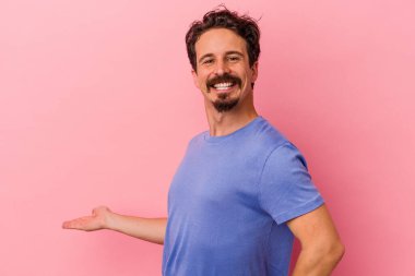Pembe arka planda izole edilmiş genç beyaz adam hoş bir yüz ifadesi sergiliyor..