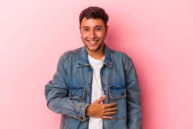 Sarı arka planda izole edilmiş beyaz dövmeli genç bir adam karnına dokunuyor, nazikçe gülümsüyor, yemek yiyor ve tatmin oluyor..