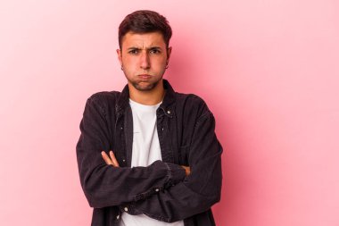 Sarı arka planda izole edilmiş dövmeleri olan beyaz genç bir adam yanakları patlatıyor, yorgun bir ifade takınıyor. Yüz ifadesi kavramı.