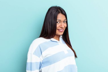 Genç Venezuelalı bir kadın mavi arka planda izole edilmiş. Gülümsüyor, neşeli ve keyifli görünüyor..