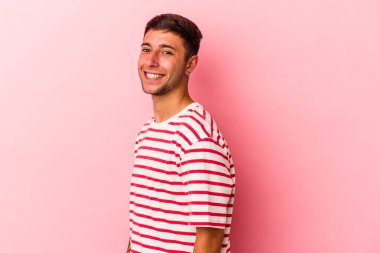 Sarı arka planda izole edilmiş dövmeleri olan genç, beyaz bir adam ellerini kalçasında tutuyor..