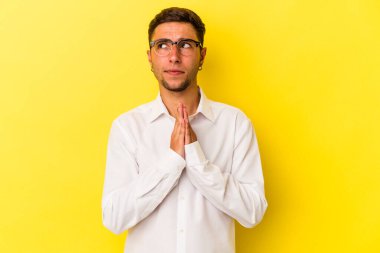 Sarı arka planda izole edilmiş dövmeleri olan genç, beyaz bir adam. Dua ediyor, bağlılık gösteriyor. İlahi ilhamı arayan dindar biri..