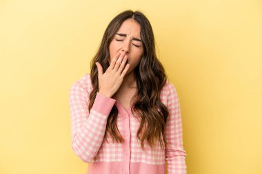 Sarı arka planda izole edilmiş genç beyaz kadın esniyor. Ağzı eliyle kapatan yorgun bir hareket sergiliyor..