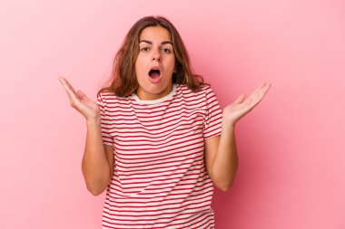 Pembe arka planda izole edilmiş genç beyaz kadın şaşırmış ve şok olmuş..