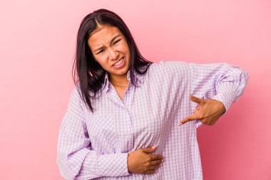 Pembe arka planda karaciğer ağrısı ve karın ağrısı çeken genç Latin bir kadın..