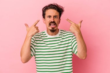 Pembe arka planda izole edilmiş genç beyaz adam işaret parmağıyla hayal kırıklığı jesti gösteriyor..