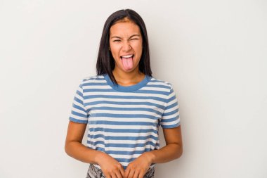 Beyaz arka planda izole edilmiş genç Latin bir kadın. Komik ve dost canlısı bir dil uzatıyor..