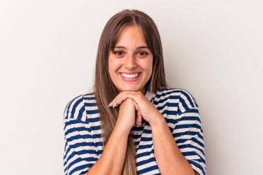 Beyaz arka planda izole edilmiş genç beyaz kadın ellerini çenesinin altında tutuyor, mutlu bir şekilde yana bakıyor..