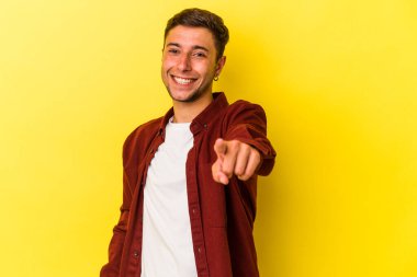 Sarı arka planda izole edilmiş dövmeli beyaz bir adam. Önü işaret eden neşeli gülümsemeler..