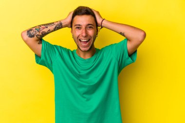 Sarı arka planda izole edilmiş dövmeleri olan genç, beyaz bir adam çığlık atıyor, çok heyecanlı, tutkulu, bir şeyden memnun..