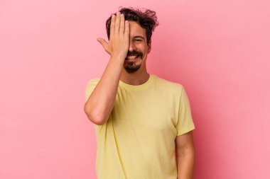 Pembe arka planda izole edilmiş genç beyaz adam yüzünün yarısını palmiye ile örterek eğleniyor..