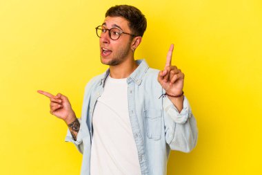 Sarı arka planda, farklı kopya alanlarını gösteren dövmeleri olan genç beyaz bir adam. Birini seçiyor, parmaklarıyla gösteriyor..