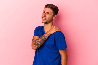 Sarı arka planda izole edilmiş, omuz ağrısı olan beyaz dövmeli genç bir adam..