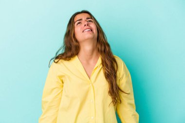 Kafkasyalı genç bir kadın mavi arka planda izole edilmiş çok kızgın, öfkeli, hayal kırıklığına uğramış bağırıyor..