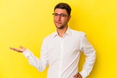 Sarı arka planda dövmeleri olan genç beyaz bir adam avuçta fotokopi alanı ve belinde bir el daha olduğunu gösteriyor..