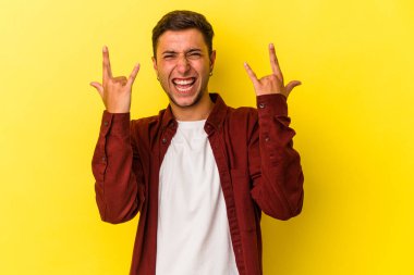 Sarı arka planda izole edilmiş dövmeleri olan genç beyaz bir adam boynuzlarını devrim konsepti olarak gösteriyor..