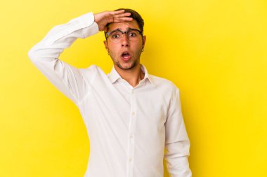 Sarı arka planda izole edilmiş dövmeleri olan genç, beyaz bir adam. Uzağa bakıyor. Alnını tutuyor..