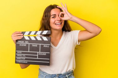 Sarı arka planda el çırpma tahtası tutan beyaz bir kadın heyecanlı..