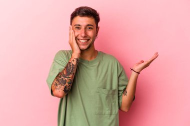 Sarı arka planda dövmeleri olan beyaz bir genç avucunun içinde fotokopi alanı tutuyor, el üstünde tutuyor. Şaşırmış ve mutlu..