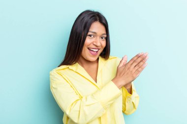 Genç Venezuelalı kadın mavi arka planda izole edilmiş enerjik ve rahat hissediyor, ellerini ovuşturuyor kendinden emin..