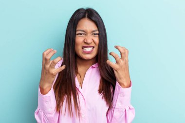 Genç Venezuelalı bir kadın mavi arka planda izole edilmiş gergin elleriyle çığlık atıyor..