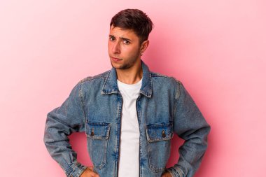 Sarı arka planda izole edilmiş dövmeleri olan genç beyaz adam kafası karışmış, şüpheli ve güvensiz hissediyor..