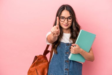 Young caucasian student woman isolated on pink background showing number one with finger.