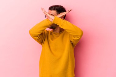 Sarı arka planda izole edilmiş, iki kolu çapraz tutan, inkar kavramı olan beyaz dövmeli genç bir adam..