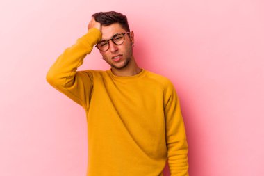 Sarı arka planda izole edilmiş dövmeleri olan genç beyaz bir adam yorgun ve uykulu bir şekilde ellerini başının üstünde tutuyor..