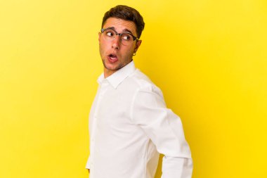 Sarı arka planda izole edilmiş dövmeleri olan beyaz bir genç gülümsüyor ve keyifli görünüyor..