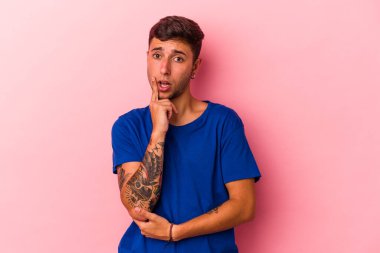 Sarı arka planda izole edilmiş, şüpheli ve şüpheci bir ifadeyle yan bakan beyaz dövmeli genç bir adam..