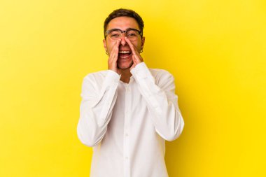 Sarı arka planda dövmeleri olan beyaz bir genç adam dedikodu yapıyor, bir şeyleri haber veriyor..