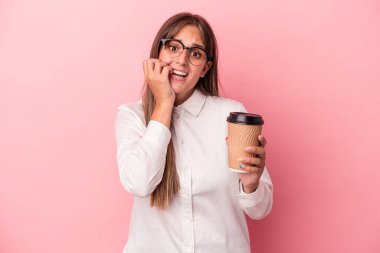 Pembe arka planda izole edilmiş, tırnak yiyen, gergin ve tedirgin genç beyaz bir kadın..