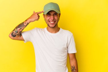 Sarı arka planda dövmeleri olan beyaz genç bir adam işaret parmağıyla yaptığı hayal kırıklığını gösteriyor..