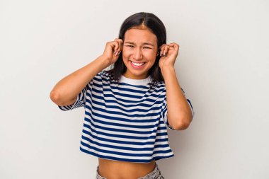 Beyaz arka planda izole edilmiş genç Latin kadın kulaklarını elleriyle kapatıyor..