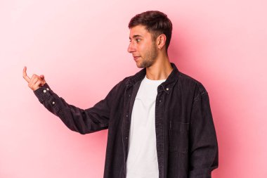 Sarı arka planda izole edilmiş dövmeleri olan genç beyaz adam sanki seni davet ediyormuş gibi seni işaret ediyor..