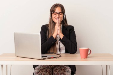 Beyaz arka planda yalnız başına seyahat eden beyaz tenli genç bir kadın el ele dua ederken, kendine güveniyor..