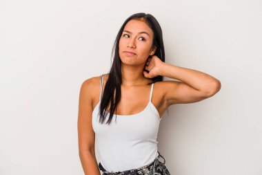 Beyaz arka planda izole edilmiş genç Latin kadın kafasının arkasına dokunuyor, düşünüyor ve bir seçim yapıyor..