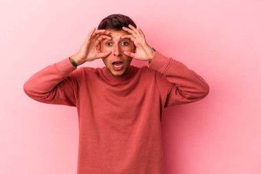 Sarı arka planda izole edilmiş dövmeleri olan beyaz genç bir adam başarılı bir fırsat yakalamak için gözlerini açık tutuyor..