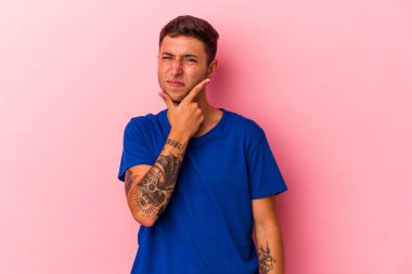 Sarı arka planda izole edilmiş dövmeleri olan genç, beyaz bir adam. Bir strateji planlıyor, bir işin nasıl olacağını düşünüyor..