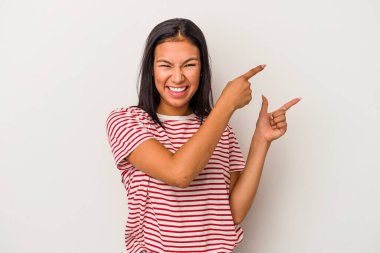 Beyaz arka planda izole edilmiş genç Latin bir kadın işaret parmağıyla işaret ederek heyecanlanıyor..