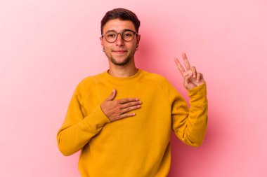 Sarı arka planda izole edilmiş dövmeleri olan beyaz genç bir adam yemin ediyor, elini göğsüne koyuyor..