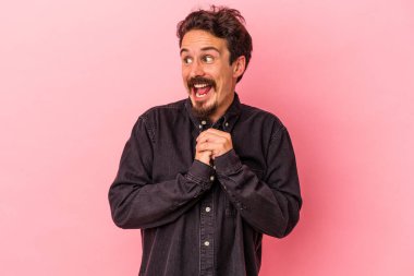 Pembe arka planda izole edilmiş genç beyaz adam şans için dua ediyor, hayrete düşüyor ve ağzını açıp önüne bakıyor..