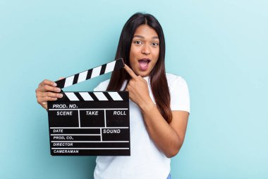 Genç Venezuelalı bir kadın mavi arka planda izole edilmiş bir alçıpan tutuyor.