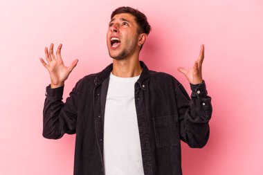 Sarı arka planda izole edilmiş dövmeleri olan genç beyaz adam gökyüzüne haykırıyor, yukarı bakıyor, hayal kırıklığına uğruyor..